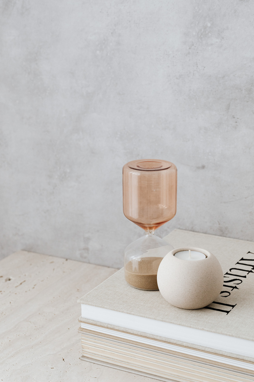 Minimalist Still Life with Beige Hourglass and a Candle on Books